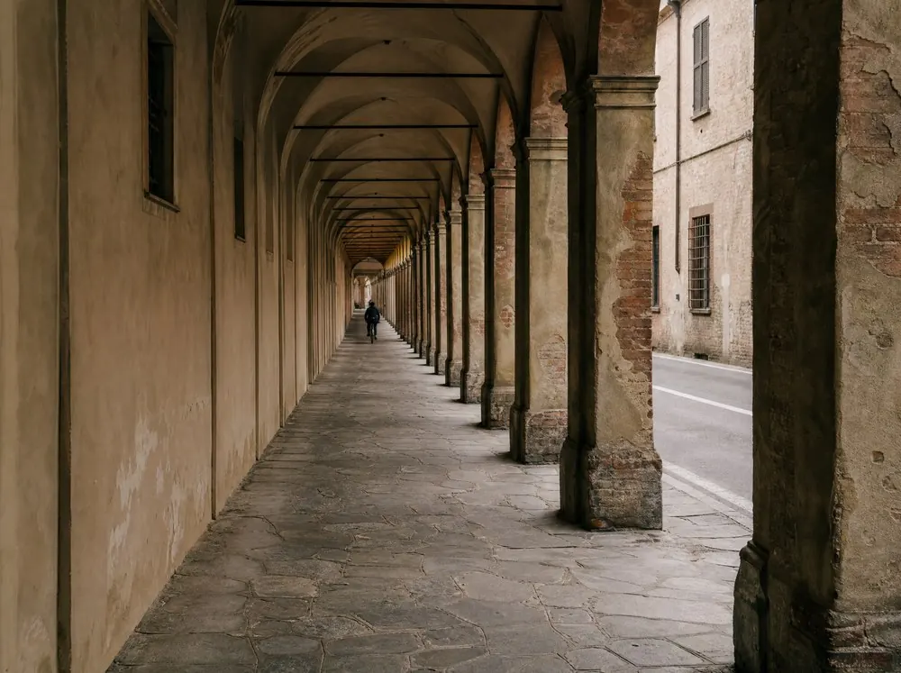 A long colonnade of stone arcades receding down a street