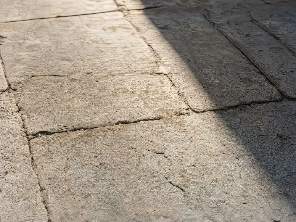 Worn pale flagstones with a hard diagonal shadow falling across them