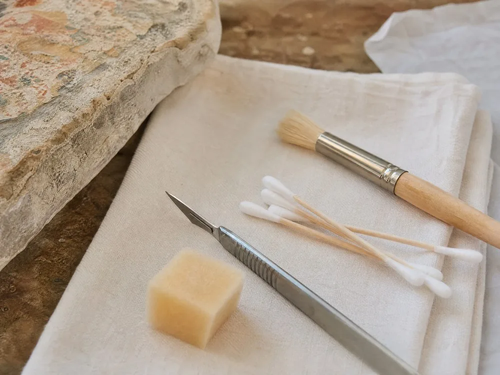 A conservator&rsquo;s scalpel, swabs and soft brush laid out on a folded cloth